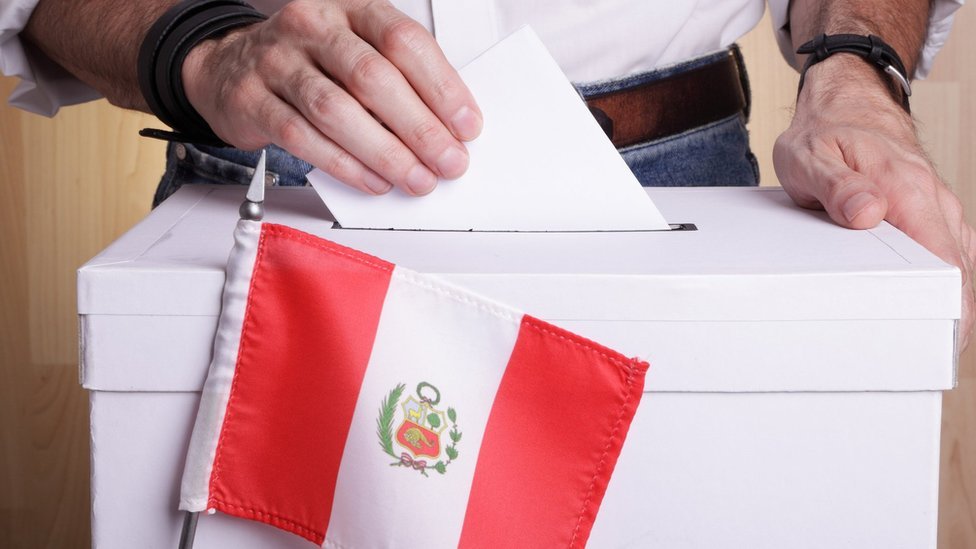 Es una persona ingresando su voto a la urna.