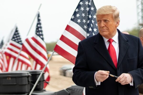 Harvard vs. Trump: Una batalla legal por el futuro de los estudiantes internacionales Trump delante de la bandera de Estados Unidos para mostrar su obsesión por el país, dejando claro que solo quiere que haya estadounidenses y nada más.