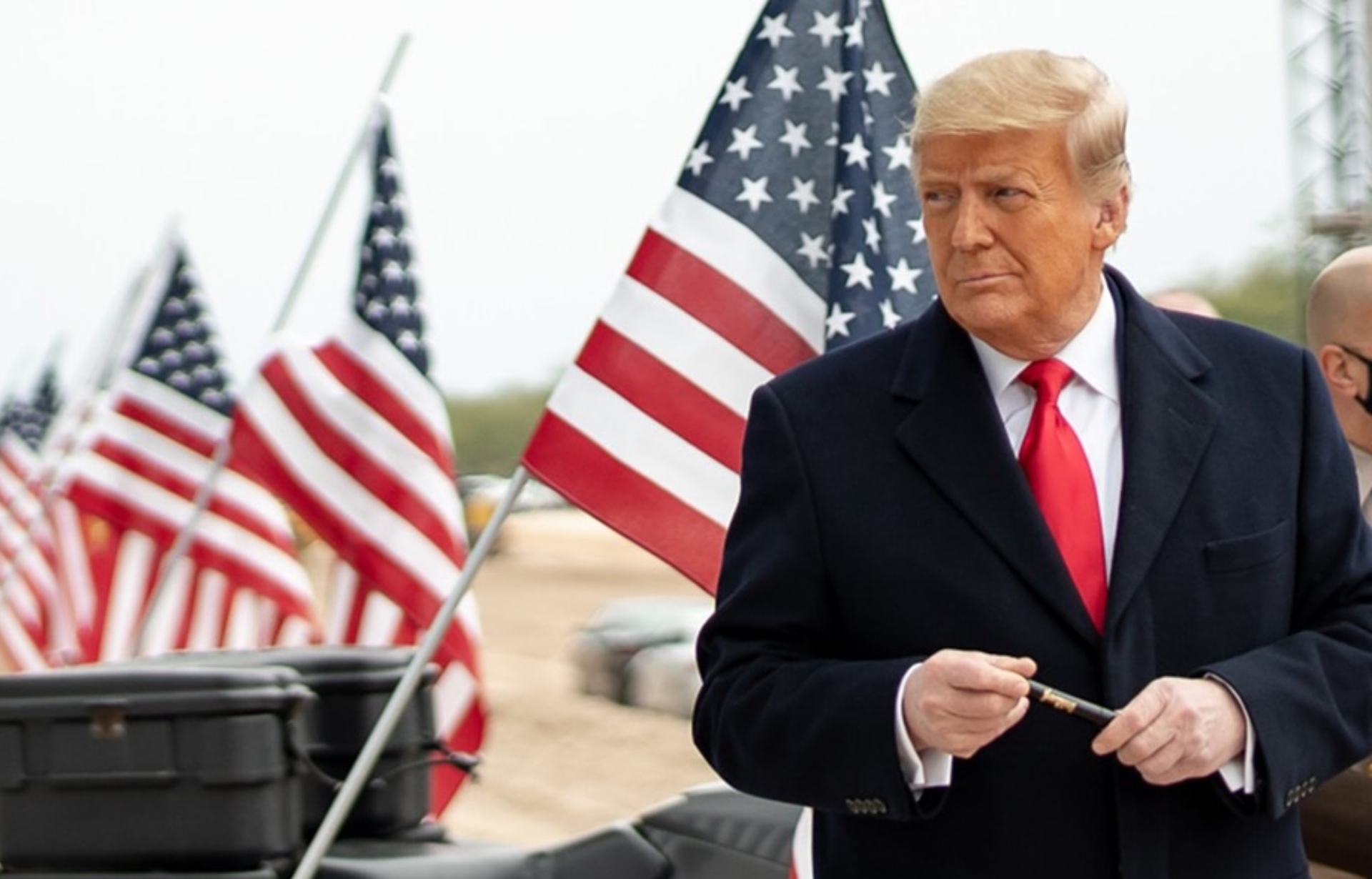 Trump delante de la bandera de Estados Unidos para mostrar su obsesión por el país, dejando claro que solo quiere que haya estadounidenses y nada más.